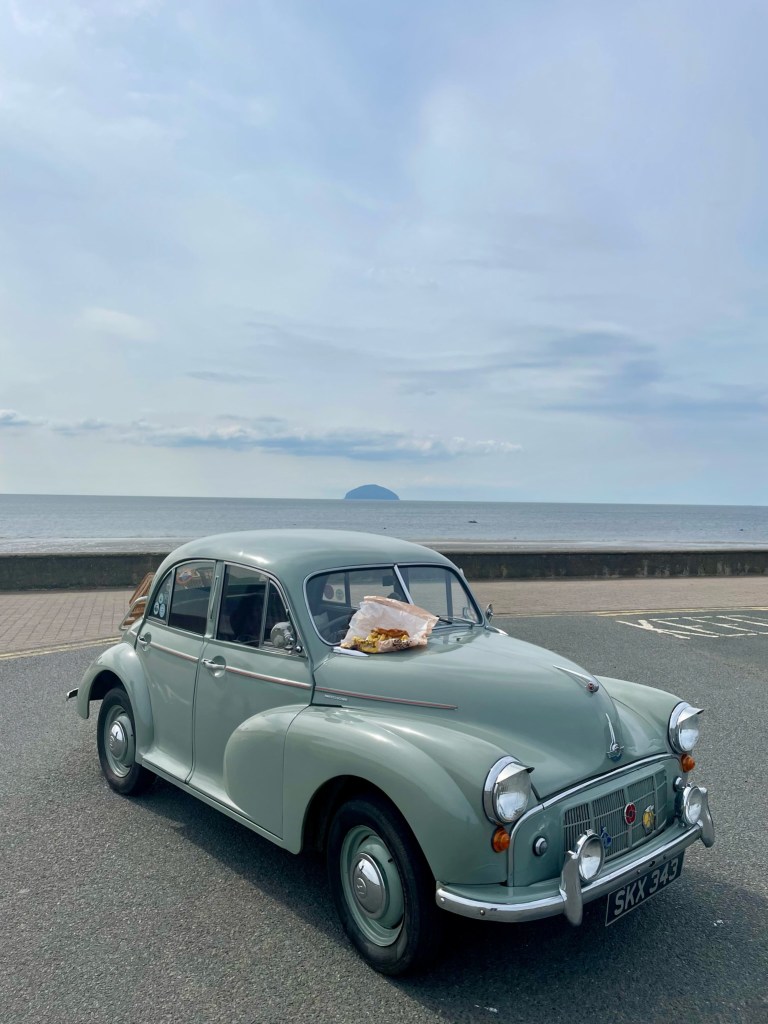 Morris Minor Series II in Girvan with sea and Ailsa Craig extinct volcano in background